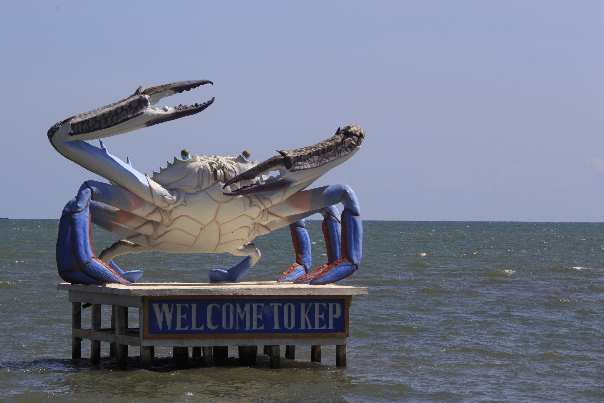 Een gigantisch krabbeeld op een platform in het water; een bord met de tekst