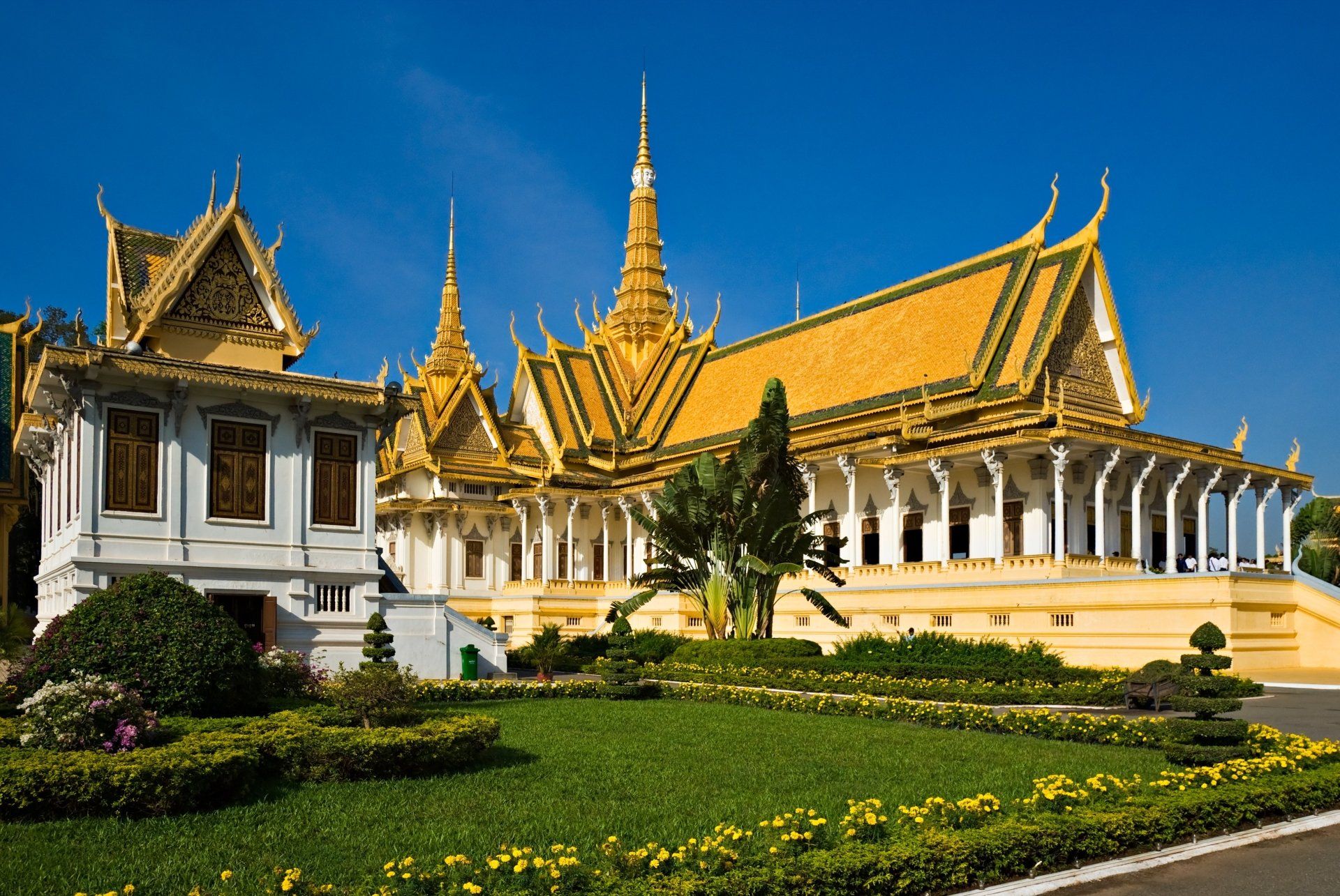 Koninklijk paleis in Phnom Penh, Cambodja, met gouden daken en perfect onderhouden tuinen onder een blauwe hemel.