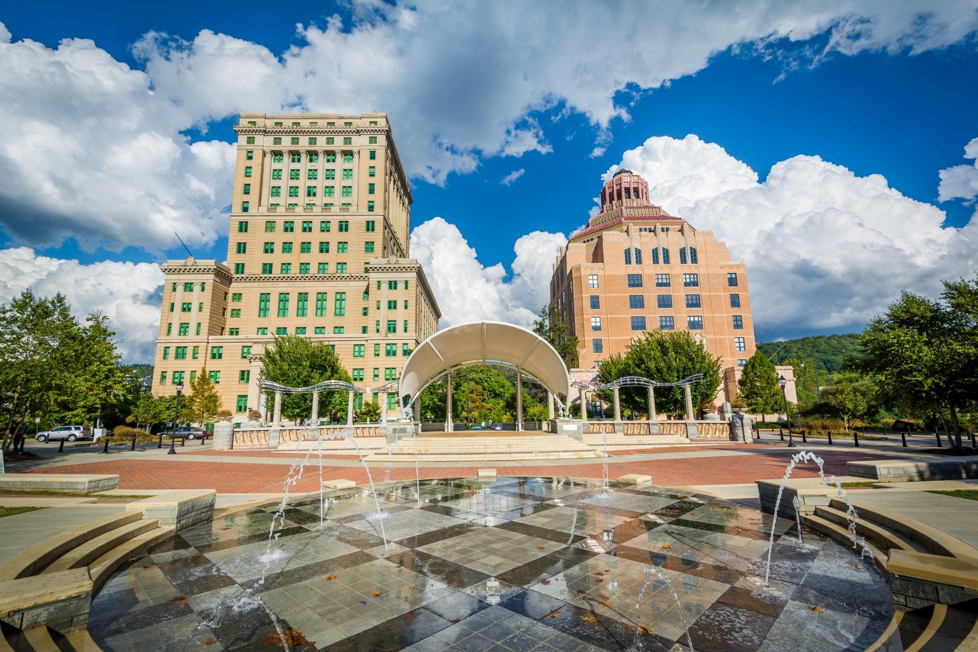 Gebouwen in het centrum van Asheville, North Carolina, met een fontein op de voorgrond en een blauwe lucht met wolken.