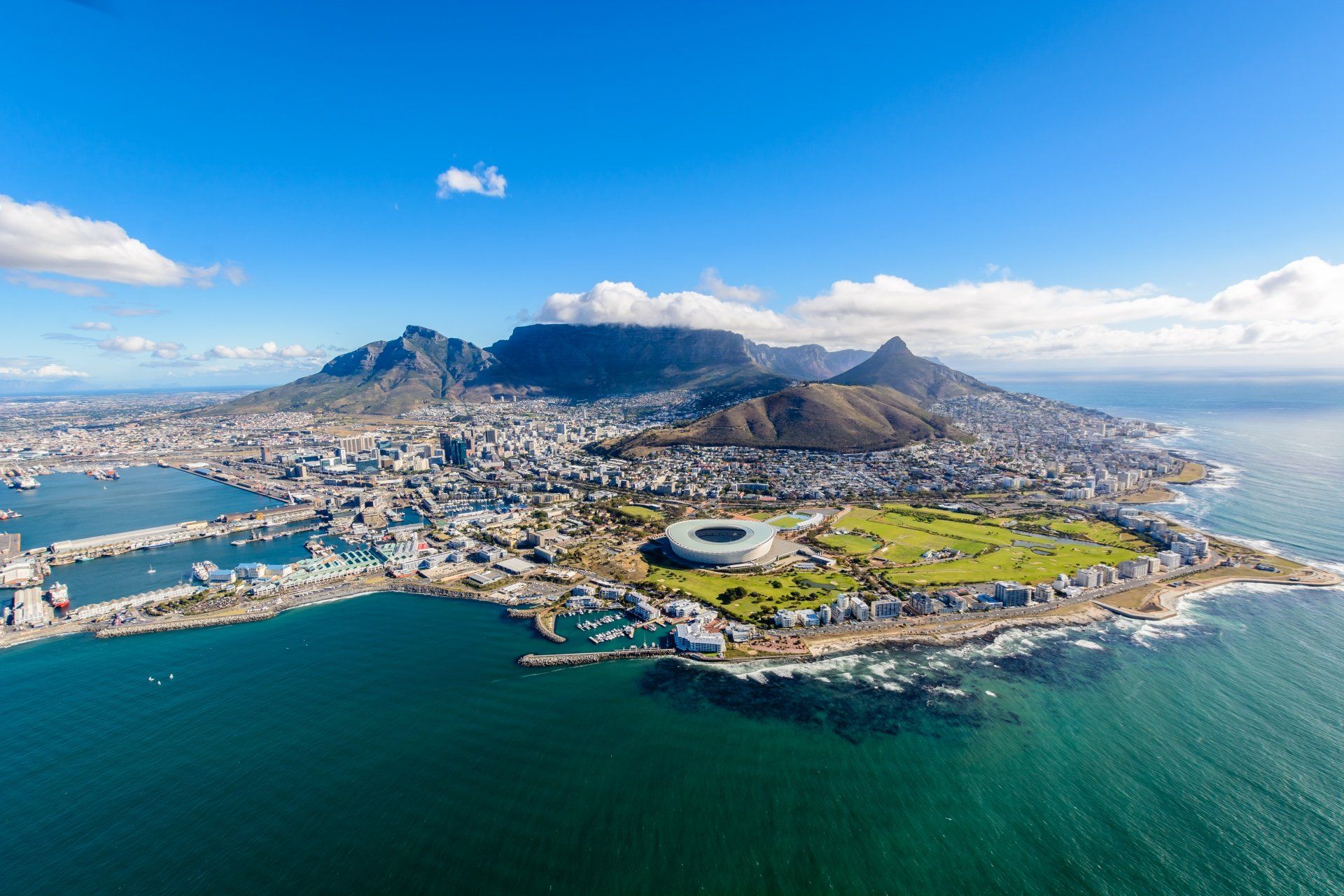 Luchtfoto van Kaapstad, Zuid-Afrika, met de Tafelberg op de achtergrond, een haven en een stadion.
