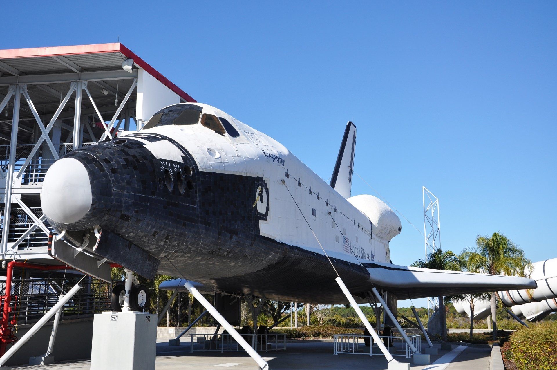De Space Shuttle Discovery staat tentoongesteld in een museum, wit en zwart tegen een blauwe lucht.