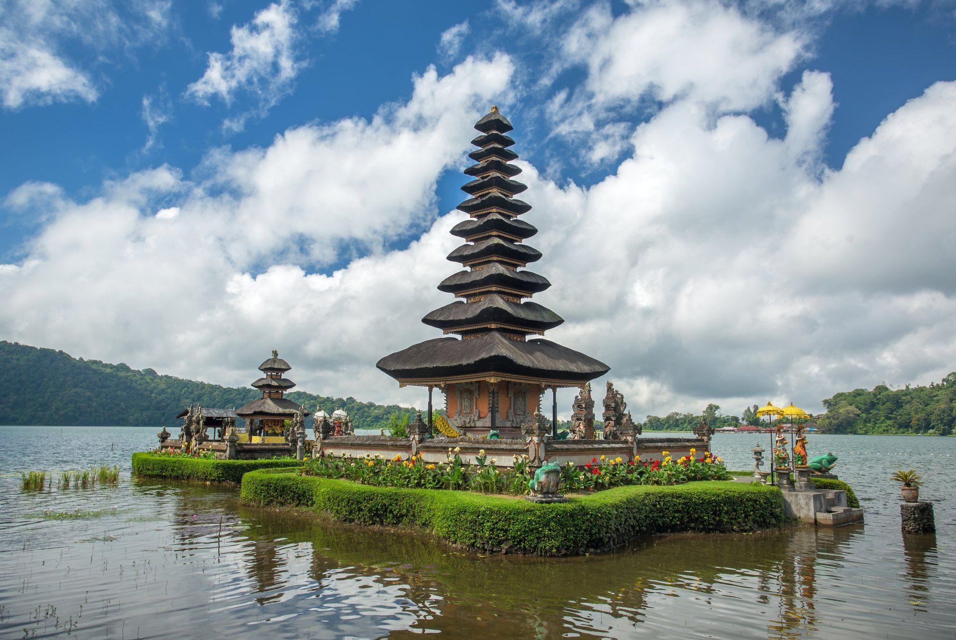 De Pura Ulun Danu Beratan-tempel ligt aan een meer onder een blauwe hemel met witte wolken.