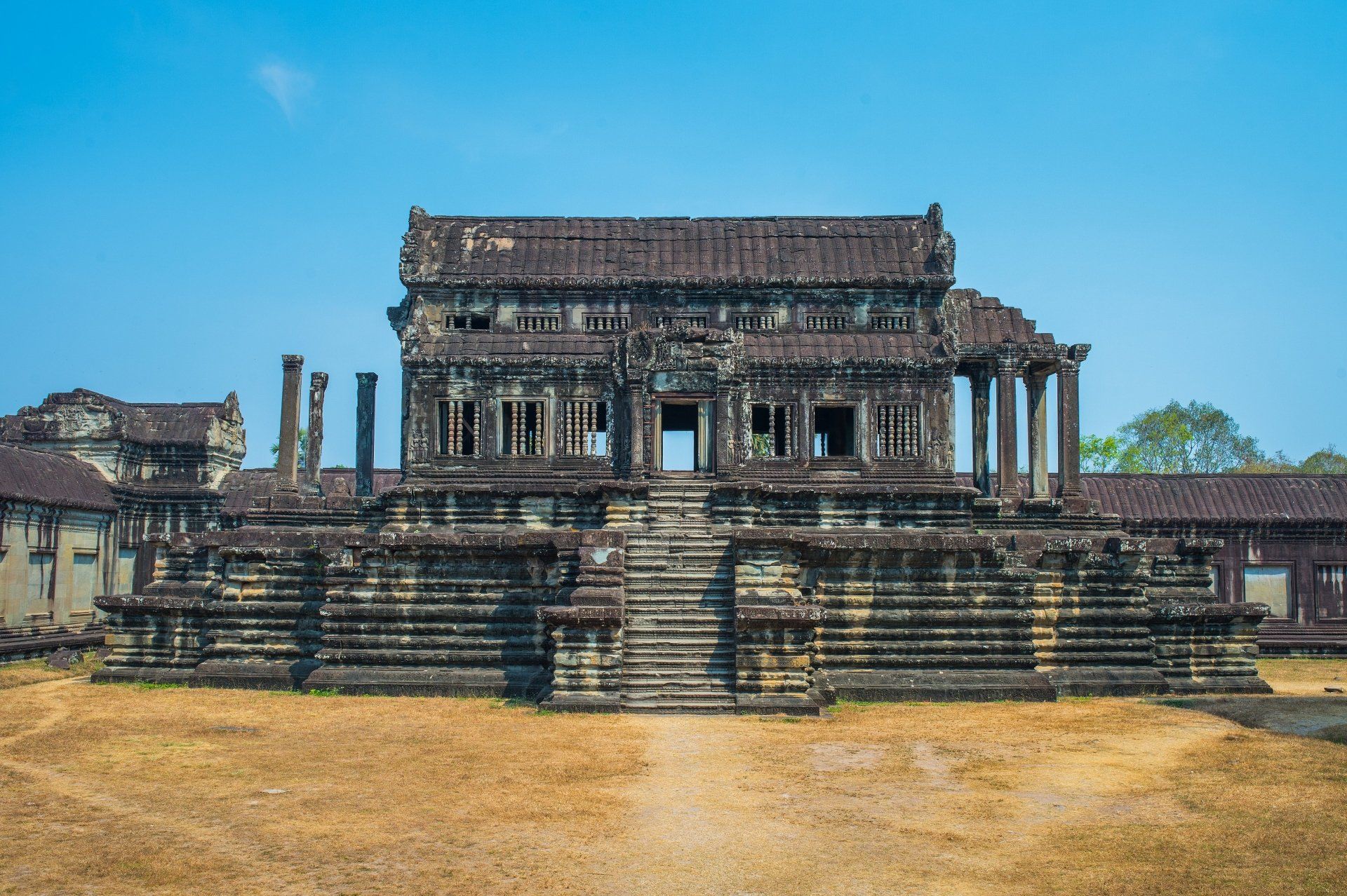 Oude stenen tempel, Angkor Wat, Cambodja, met ingewikkelde gravures, trappen en zuilen tegen een blauwe hemel.