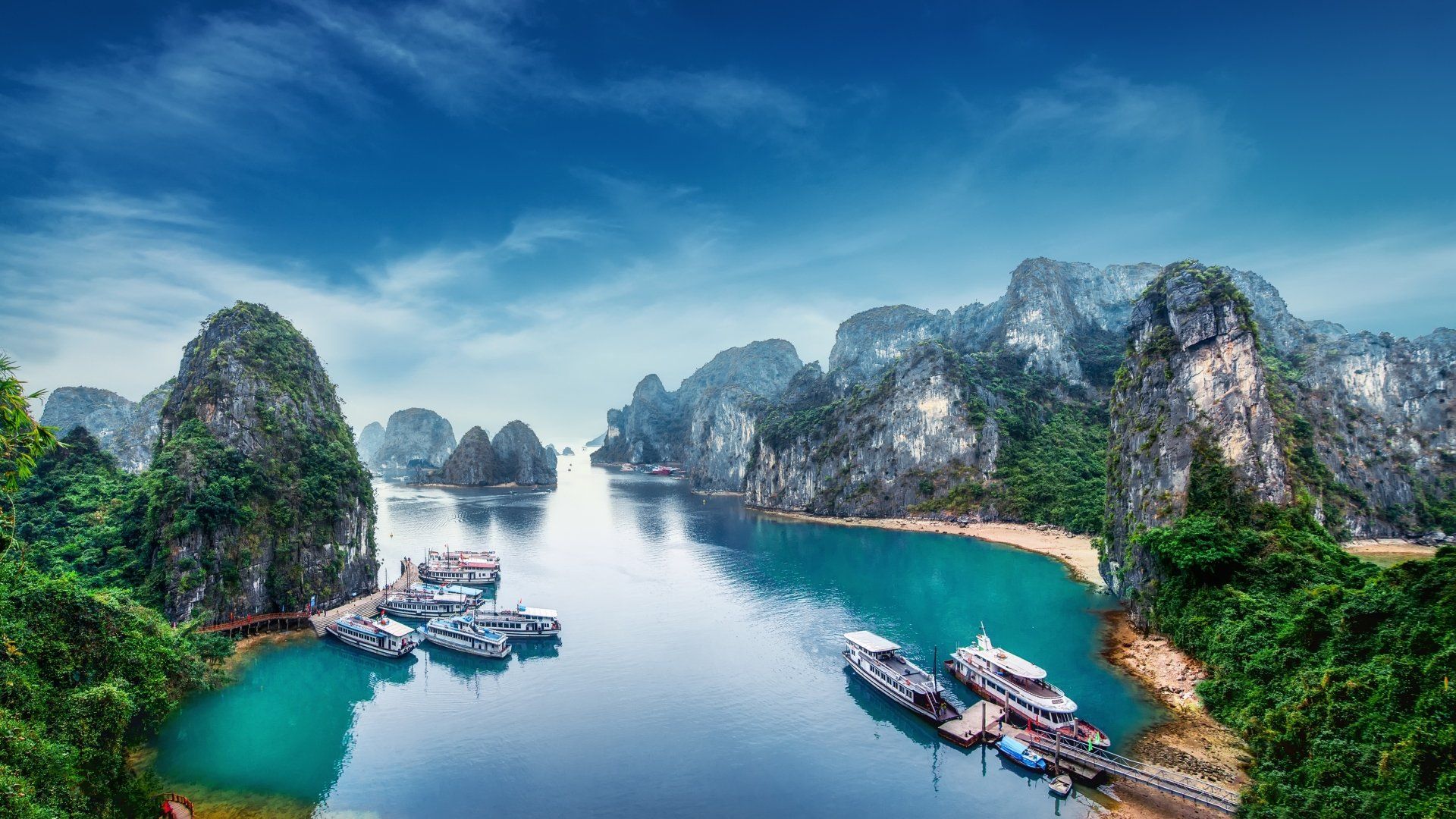 Halongbaai, Vietnam: Smaragdgroen water omgeven door kalkstenen karstformaties, aangemeerde boten.