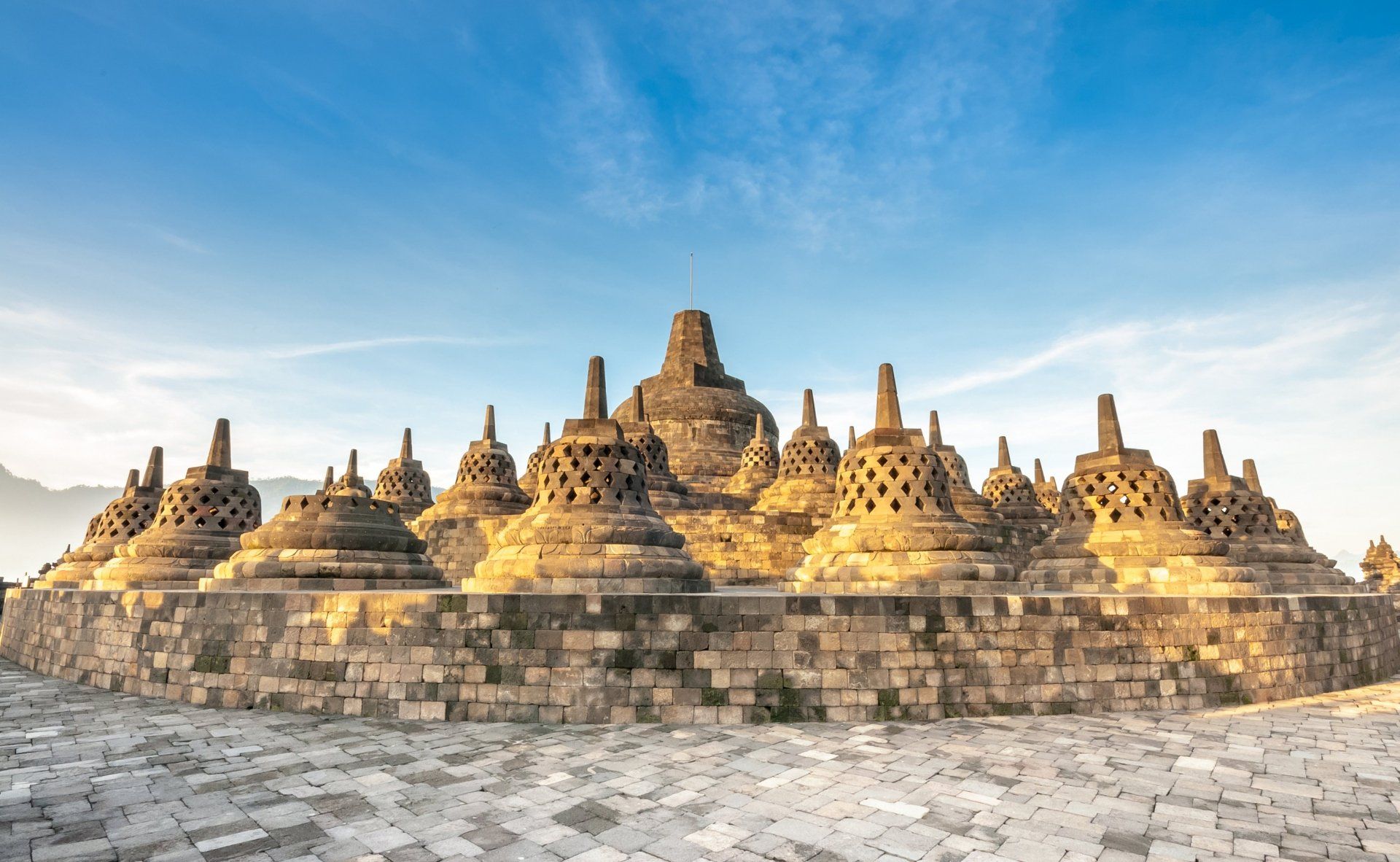 De Borobudur-tempel op Java, Indonesië. Stenen stoepa's op een terrasvormige structuur tegen een blauwe hemel.