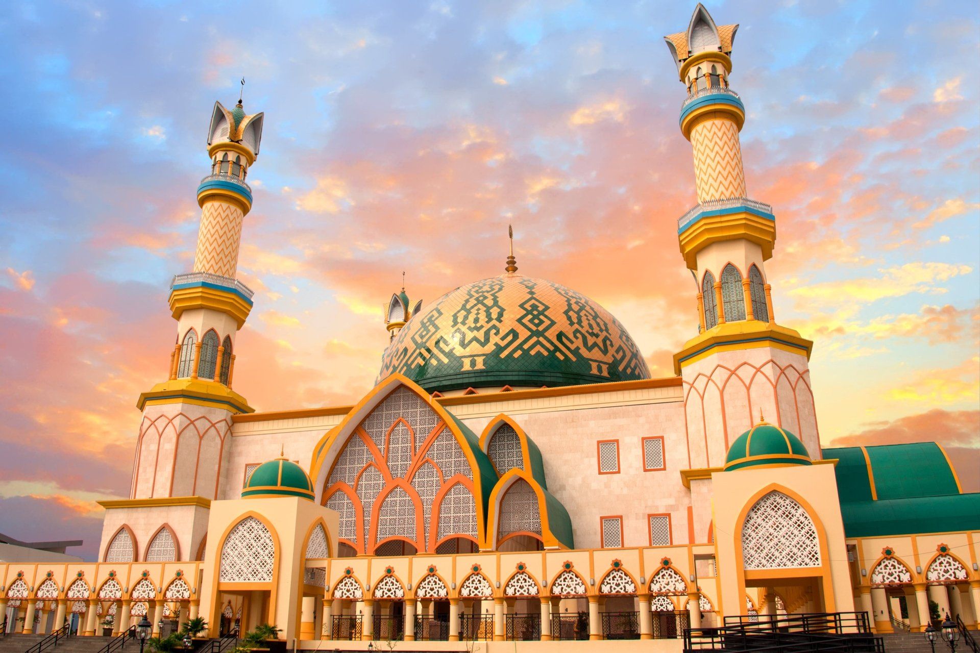 Moskee met twee hoge minaretten onder een kleurrijke zonsondergang.