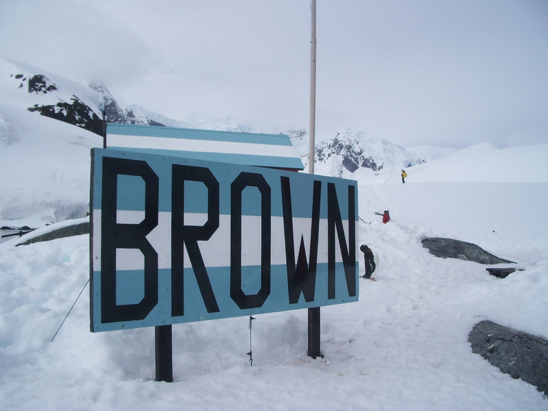 Bord met de aanduiding Brown Station, Antarctica, in de sneeuw. Het bord heeft de strepen van de Argentijnse vlag.
