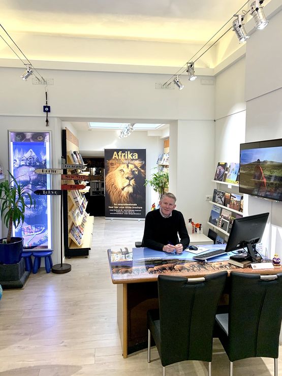 Een persoon zit aan een bureau in een reisbureau. Interieurfoto van een goed verlicht kantoor met reisaffiches en -brochures.