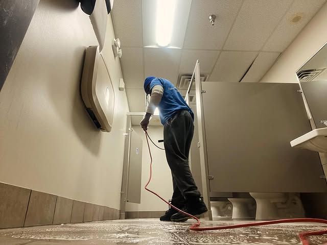 A man in a blue shirt is cleaning a bathroom floor
