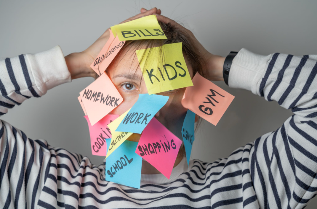 A person in a striped shirt holds their head with both hands, face nearly covered by colorful sticky