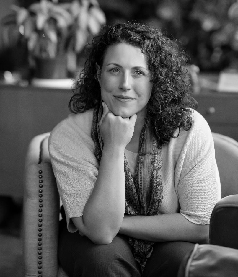 Person seated indoors, resting chin on hand, with a relaxed expression.