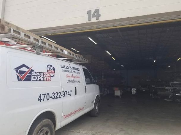A white van is parked in front of a garage door.