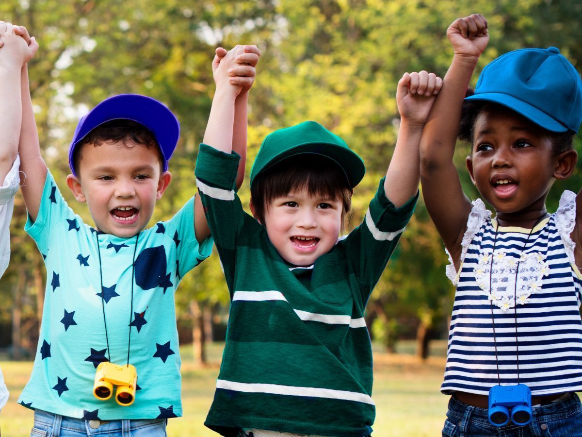 A group of children are holding their hands up in the air.