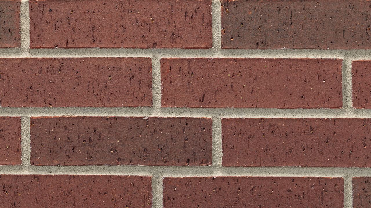 A close up of a red brick wall with white trim.