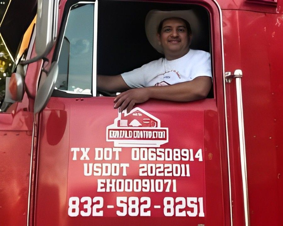 A man in a cowboy hat is sitting in the driver 's seat of a red truck.