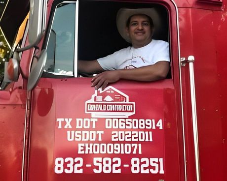 A man in a cowboy hat is sitting in the driver 's seat of a red truck.