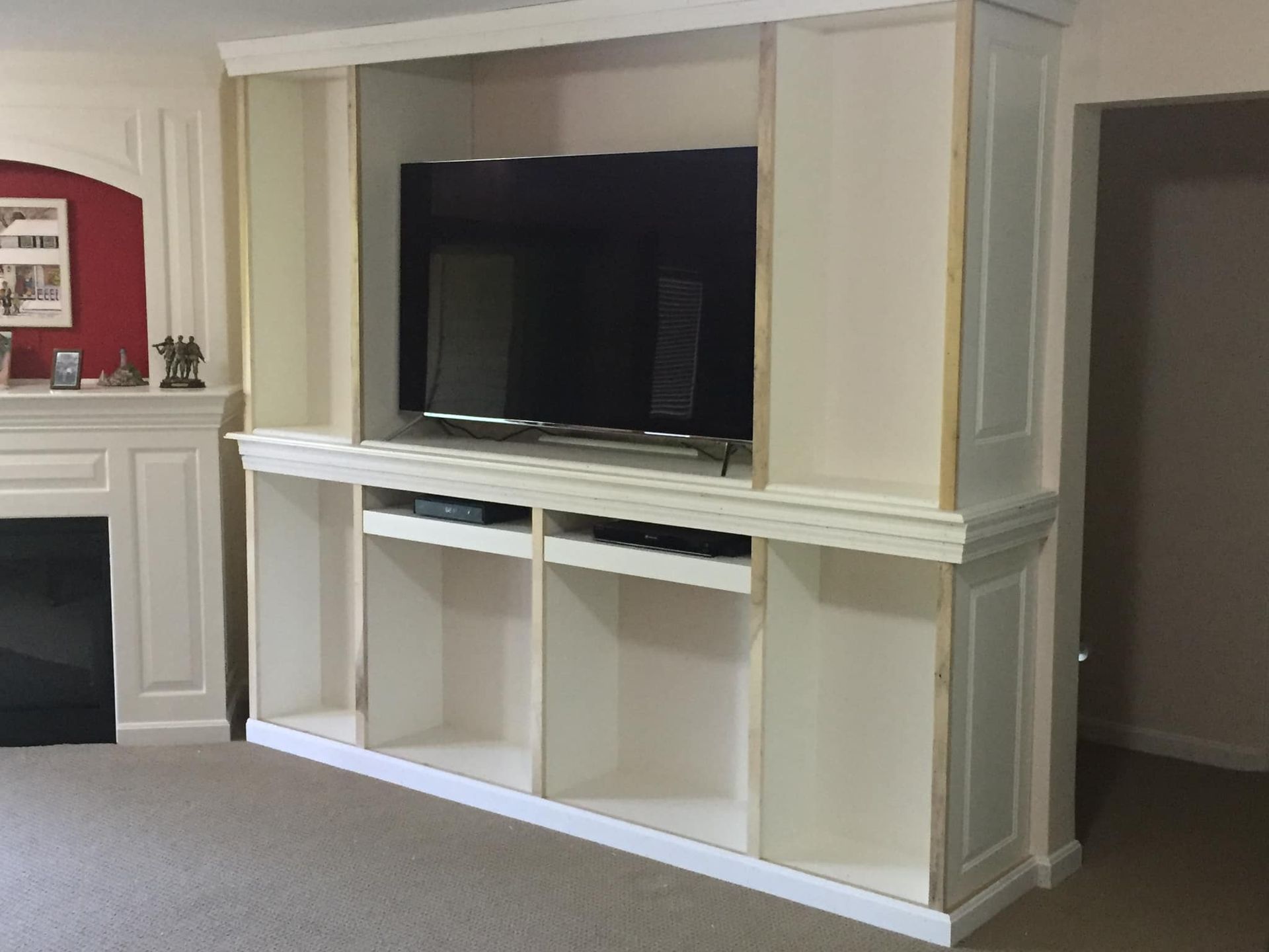 Built-in white entertainment center with TV, open shelves, and cabinets. Located in a living room.