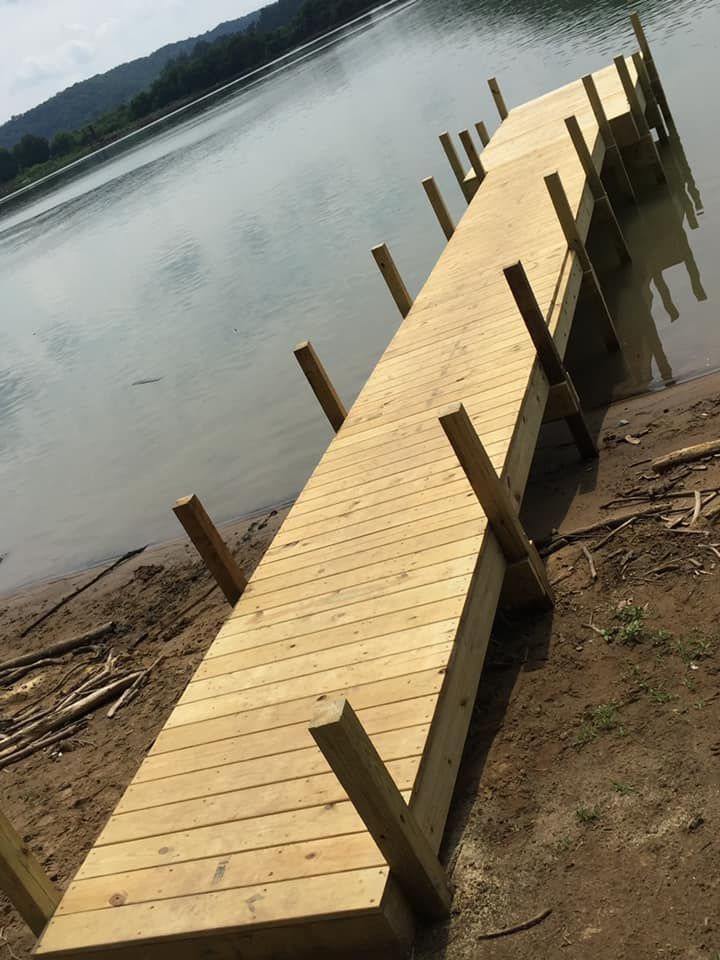 Wooden dock extending into a body of water, built on a shoreline.