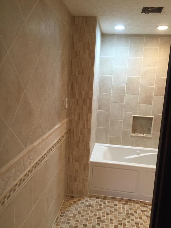 Bathroom with beige tiles, a bathtub, and recessed lighting.