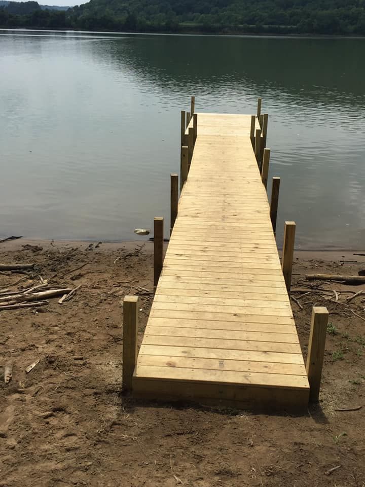Wooden dock extending into calm water, against a backdrop of a distant shoreline.