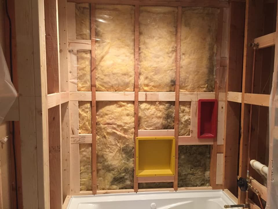 Bathroom wall framing with insulation, a tub, and built-in niches.