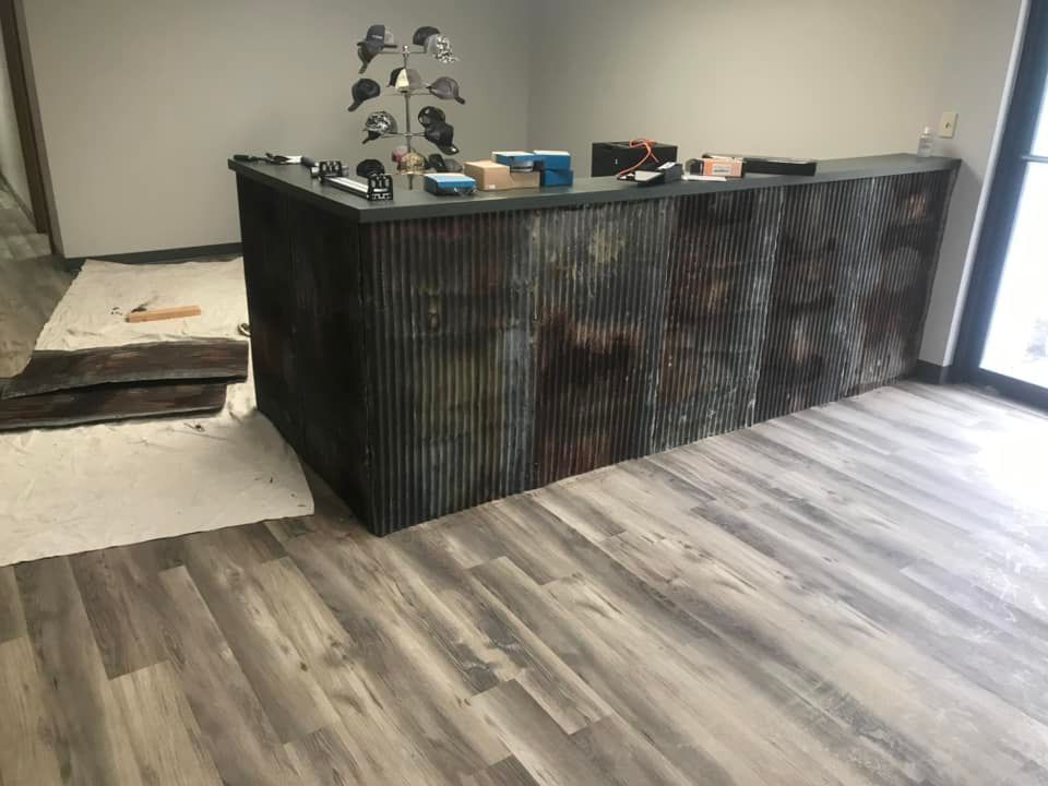 Reception desk with corrugated metal siding, wood floor, and items on top.