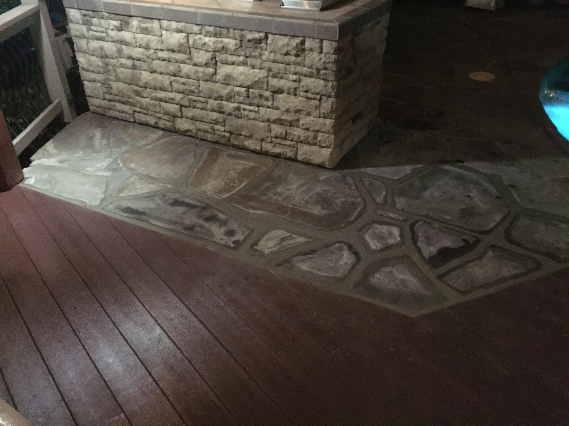 Outdoor deck with stone and wood surfaces. A stone-covered bar is in the background.