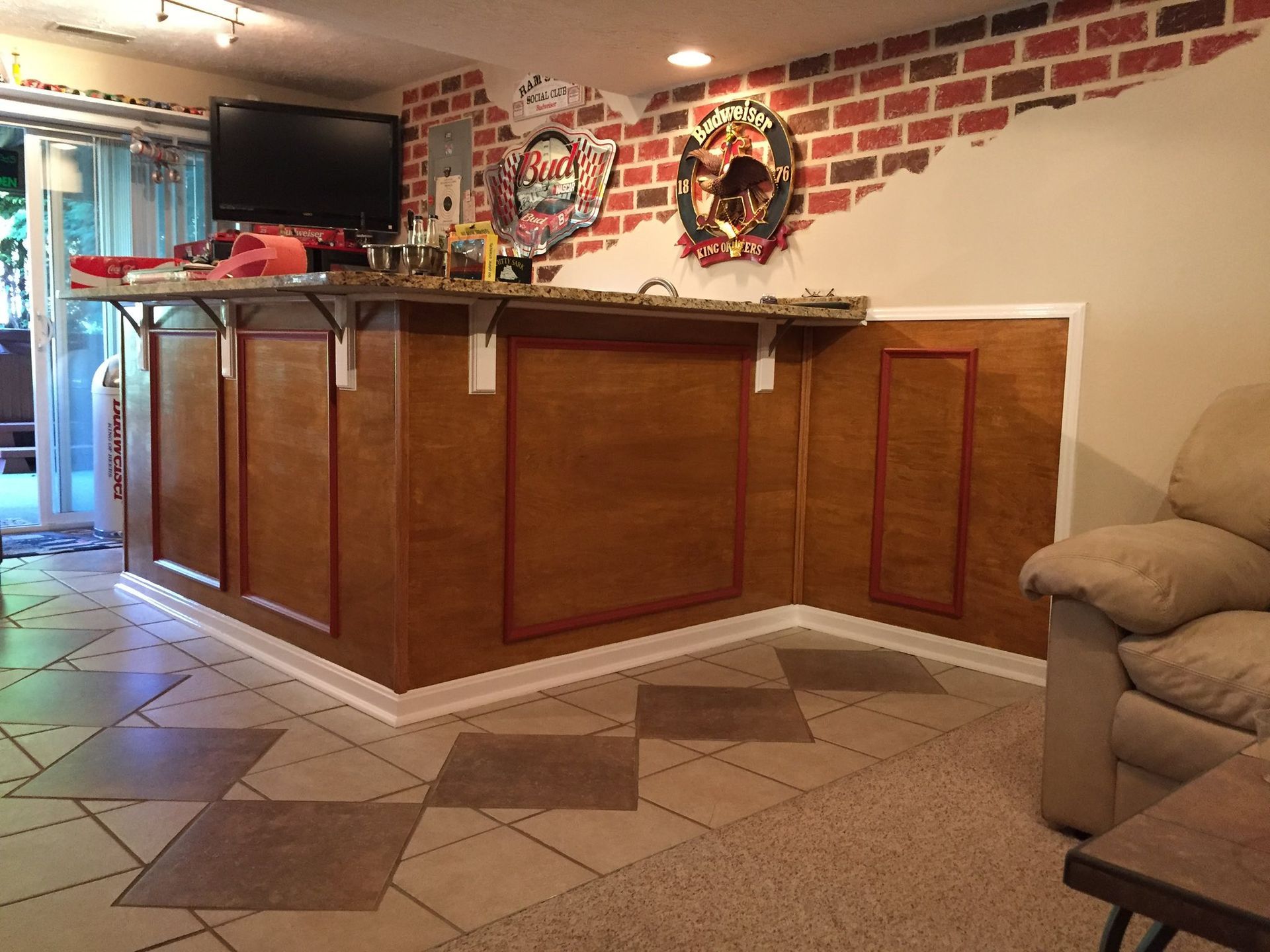 Home bar with wood paneling, red brick wall, and decorative floor tiles.
