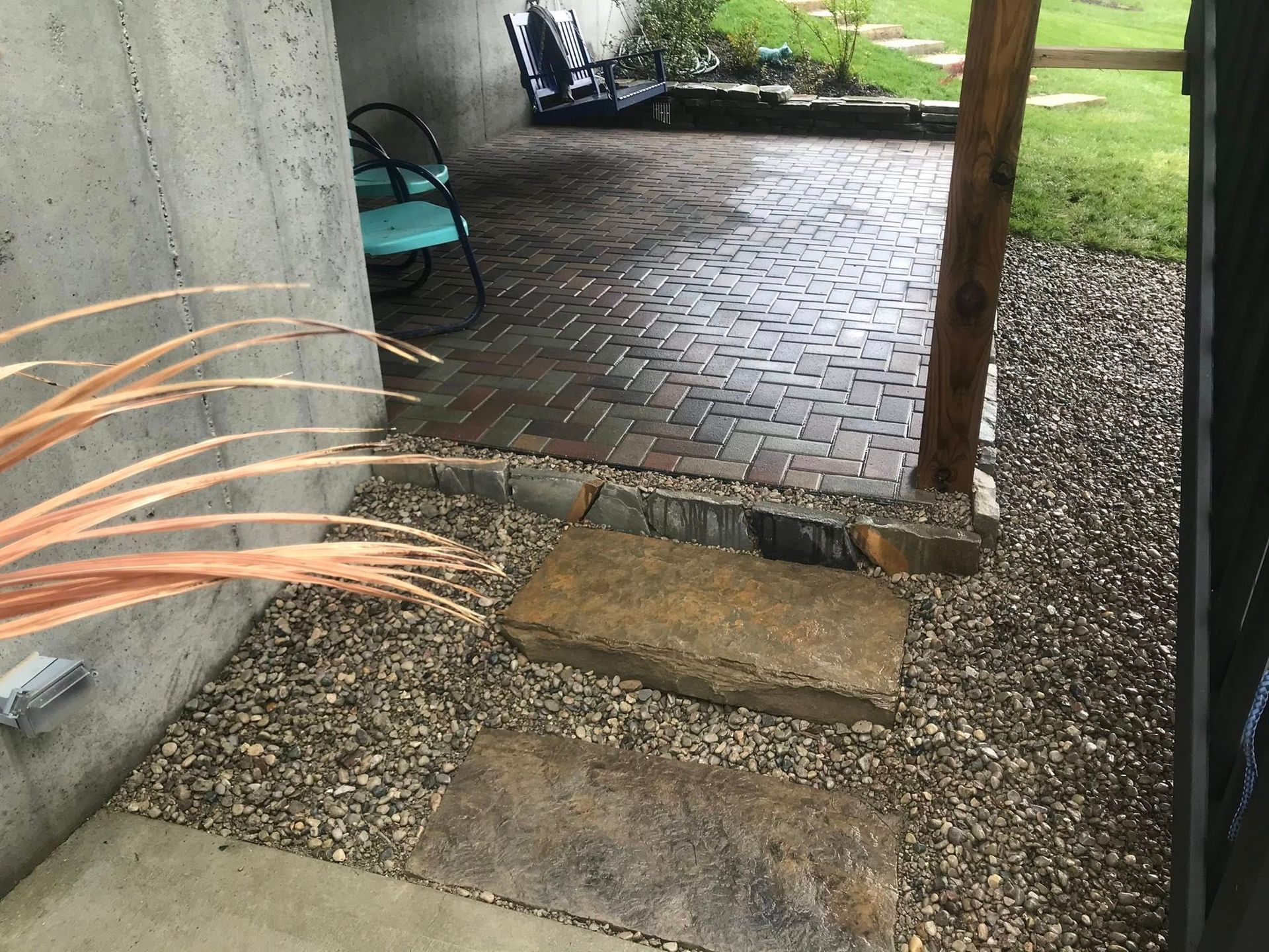 Brick patio with gravel pathway and stone steps leading to seating area.
