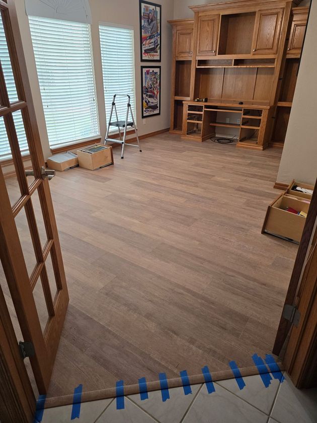 Empty room with wood floor, built-in shelving, and large windows with blinds.