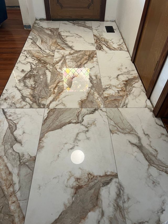 Marble-pattern tiled hallway floor with glossy finish and a small square drain near the back wall