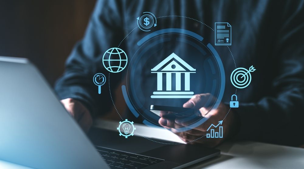 Person using a laptop with a glowing bank icon and finance symbols on screen