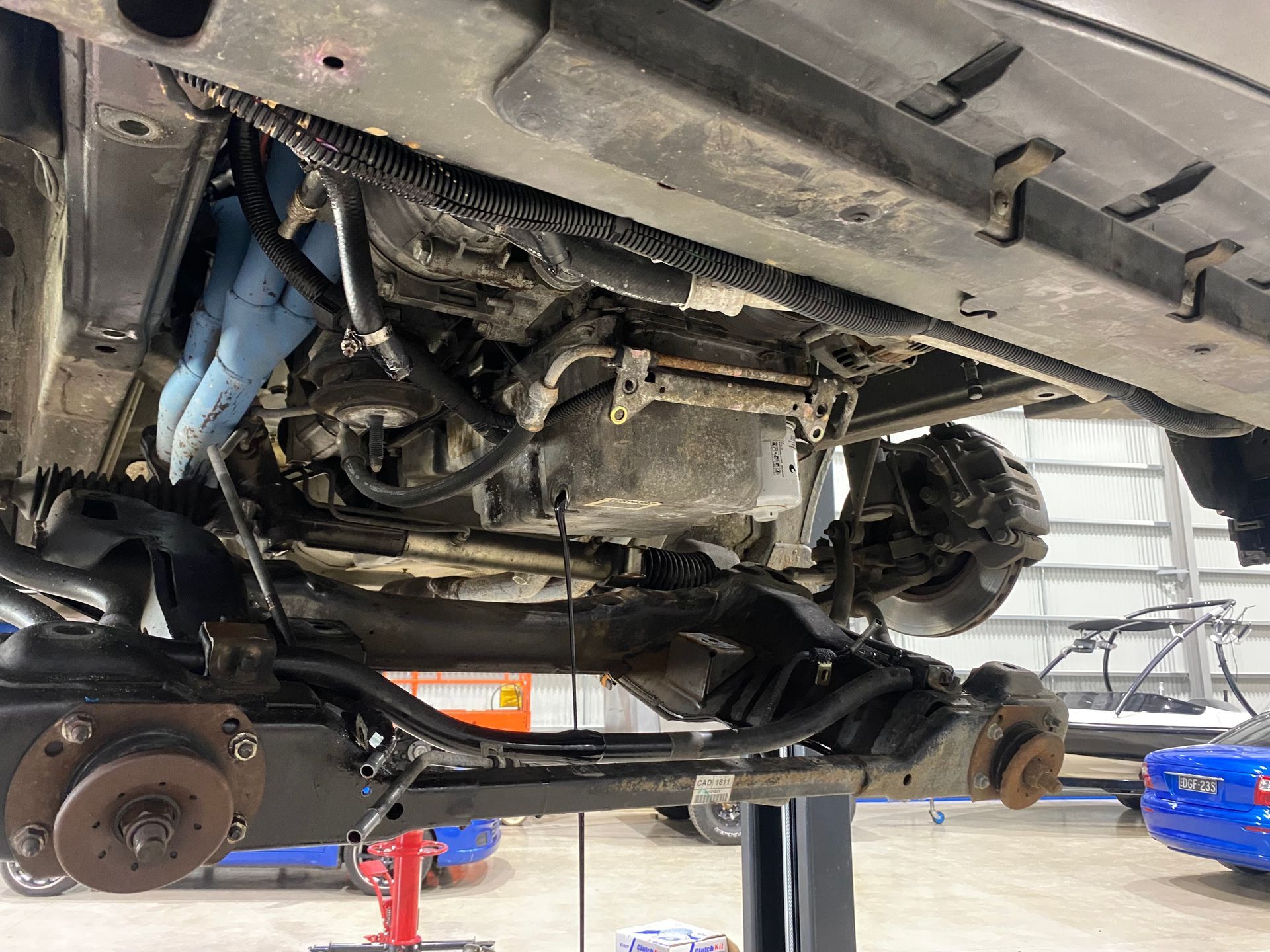 Car Engine is Being Worked on in a Garage With a Blue Hose Attached to It — NG Mechanical Services in Thurgoona, NSW