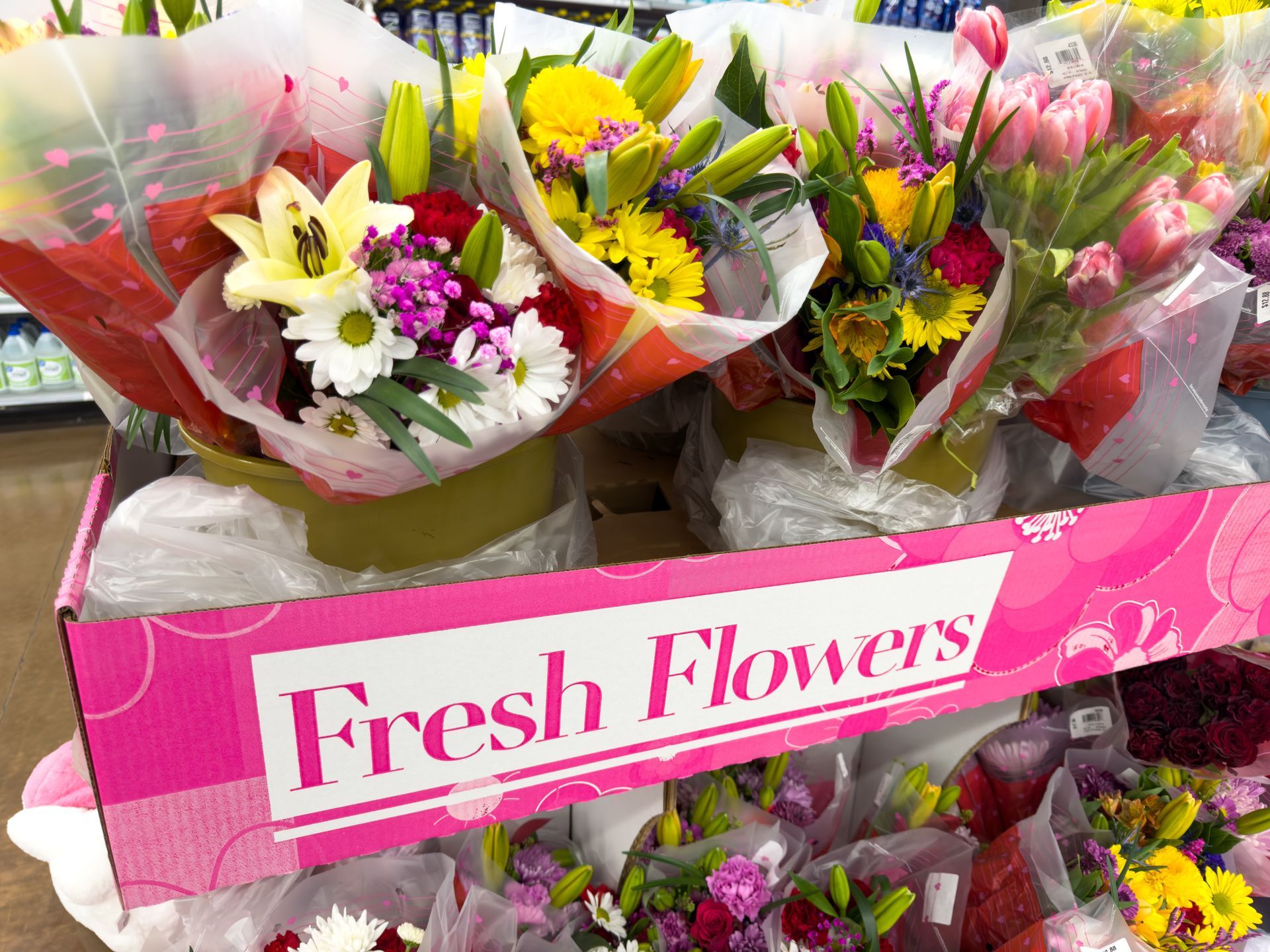 Assorted colorful fresh flower bouquets displayed in a shop with a pink “Fresh Flowers” sign