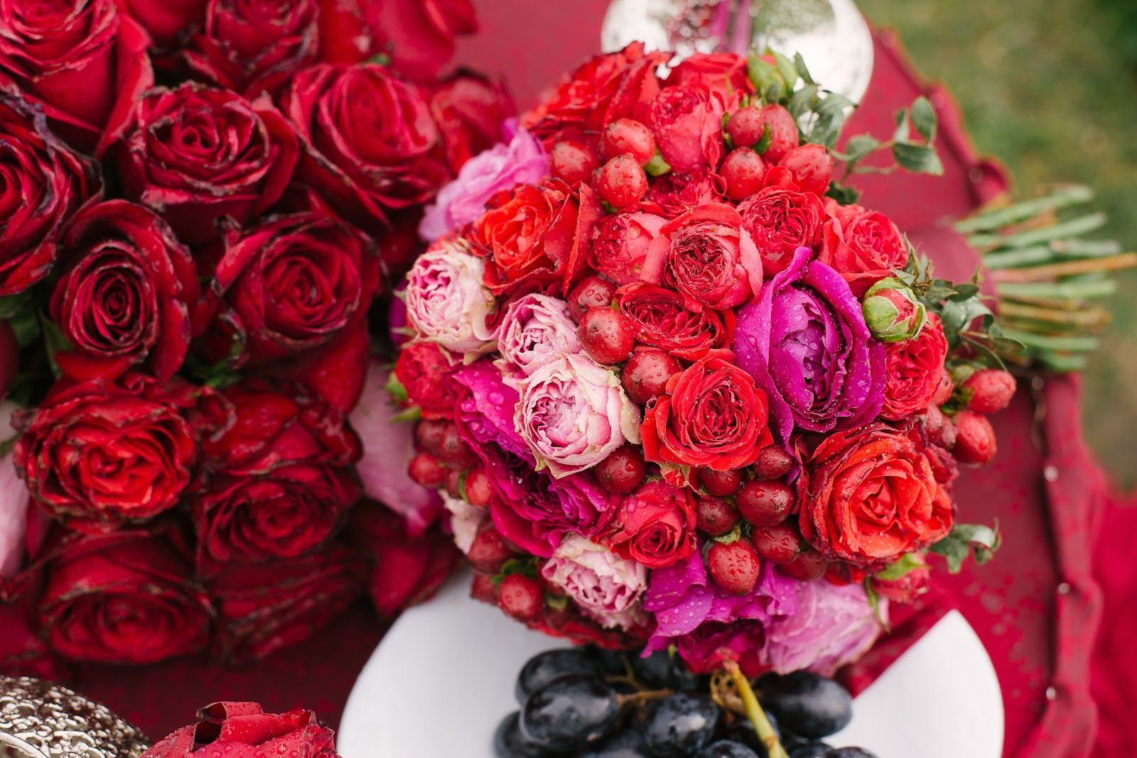 Red and pink rose bouquets arranged on a table with decorative ribbons and foliage