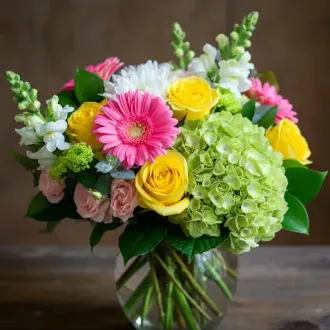 A vase filled with pink and yellow flowers on a table