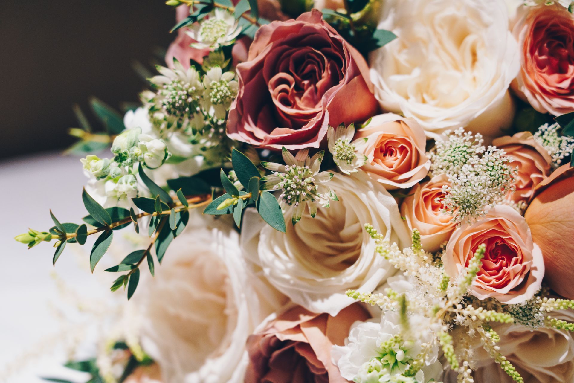 Assorted pink, cream, and white roses with greenery in a floral bouquet