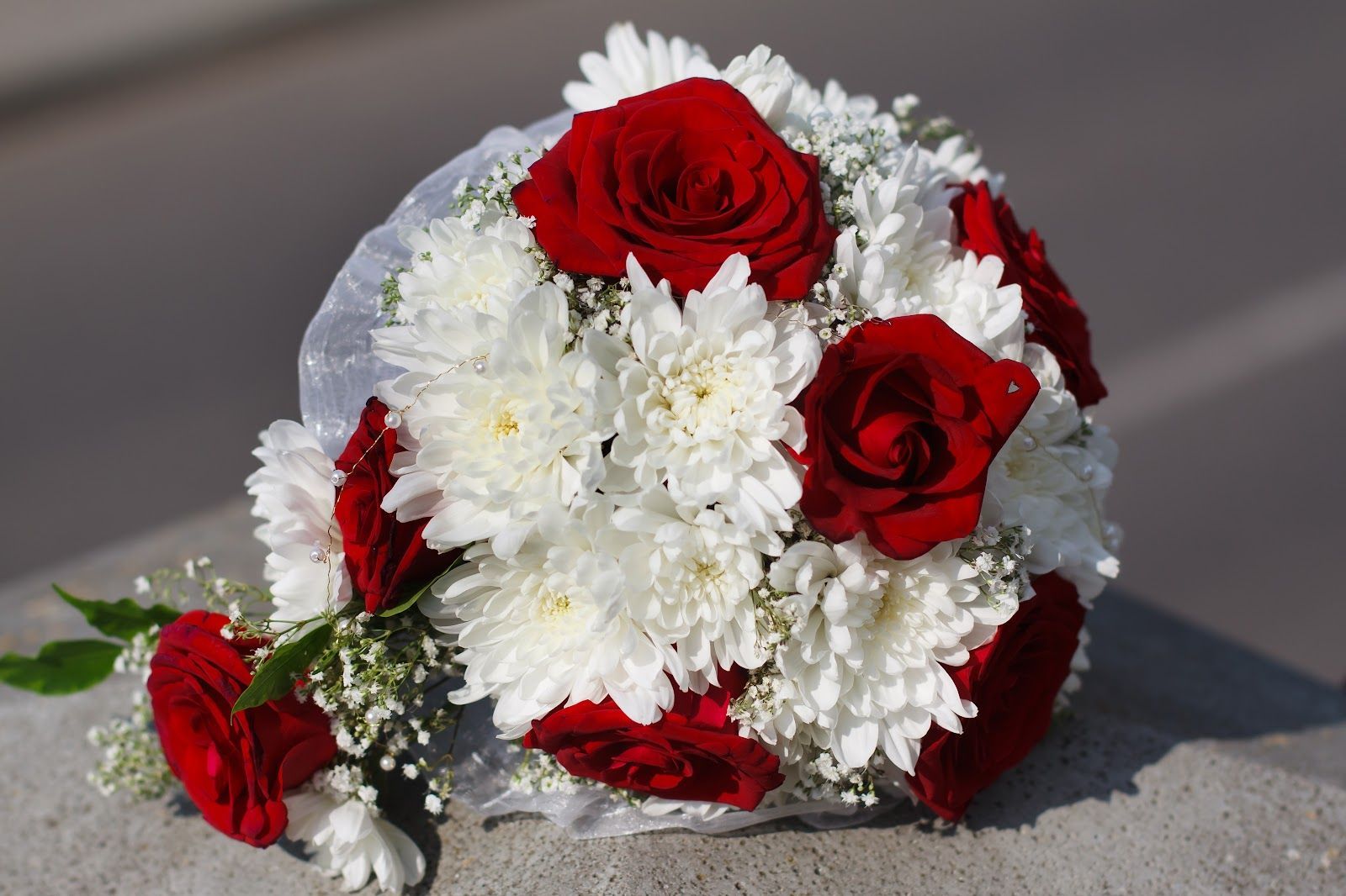 White and red flower bouquet resting on a gray surface
