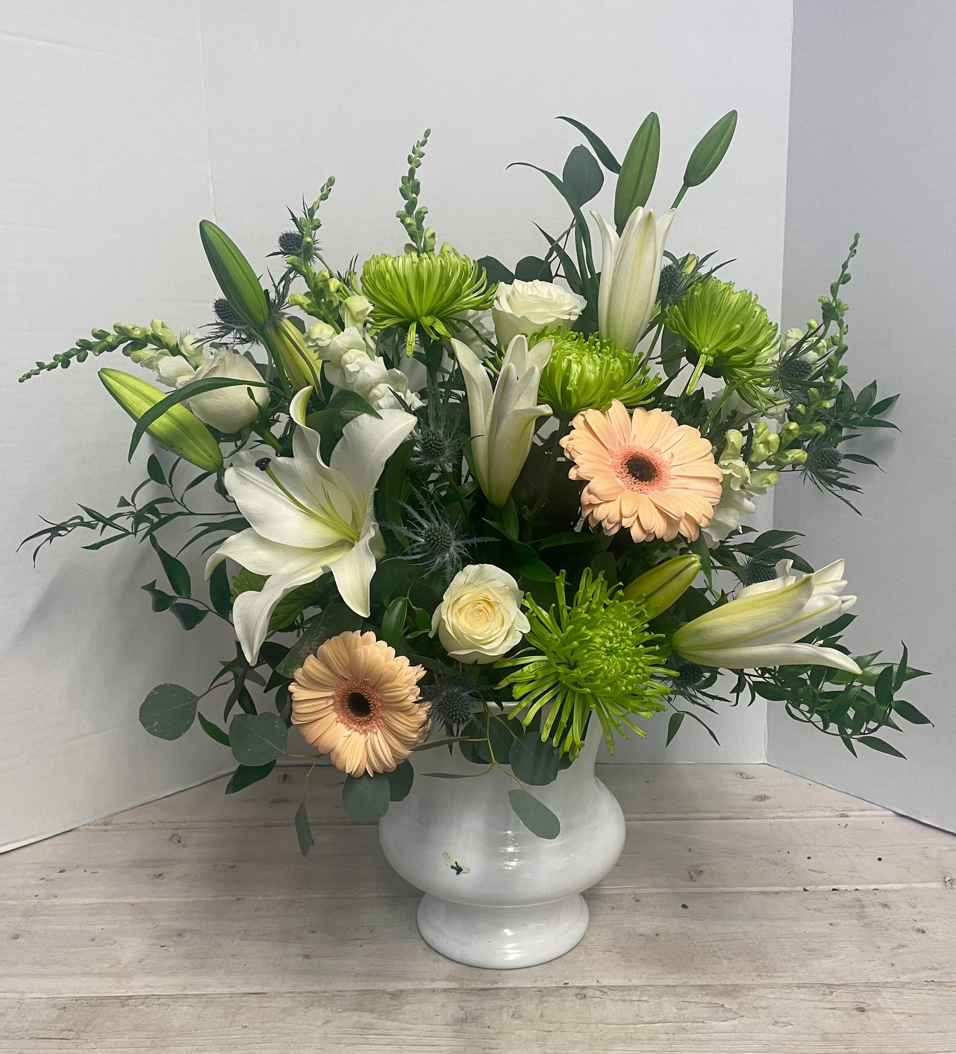 a white vase filled with flowers is sitting on a wooden table