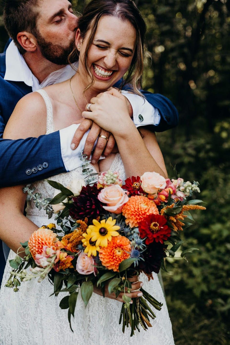 a man kisses a woman on the cheek while she holds a bouquet of flowers