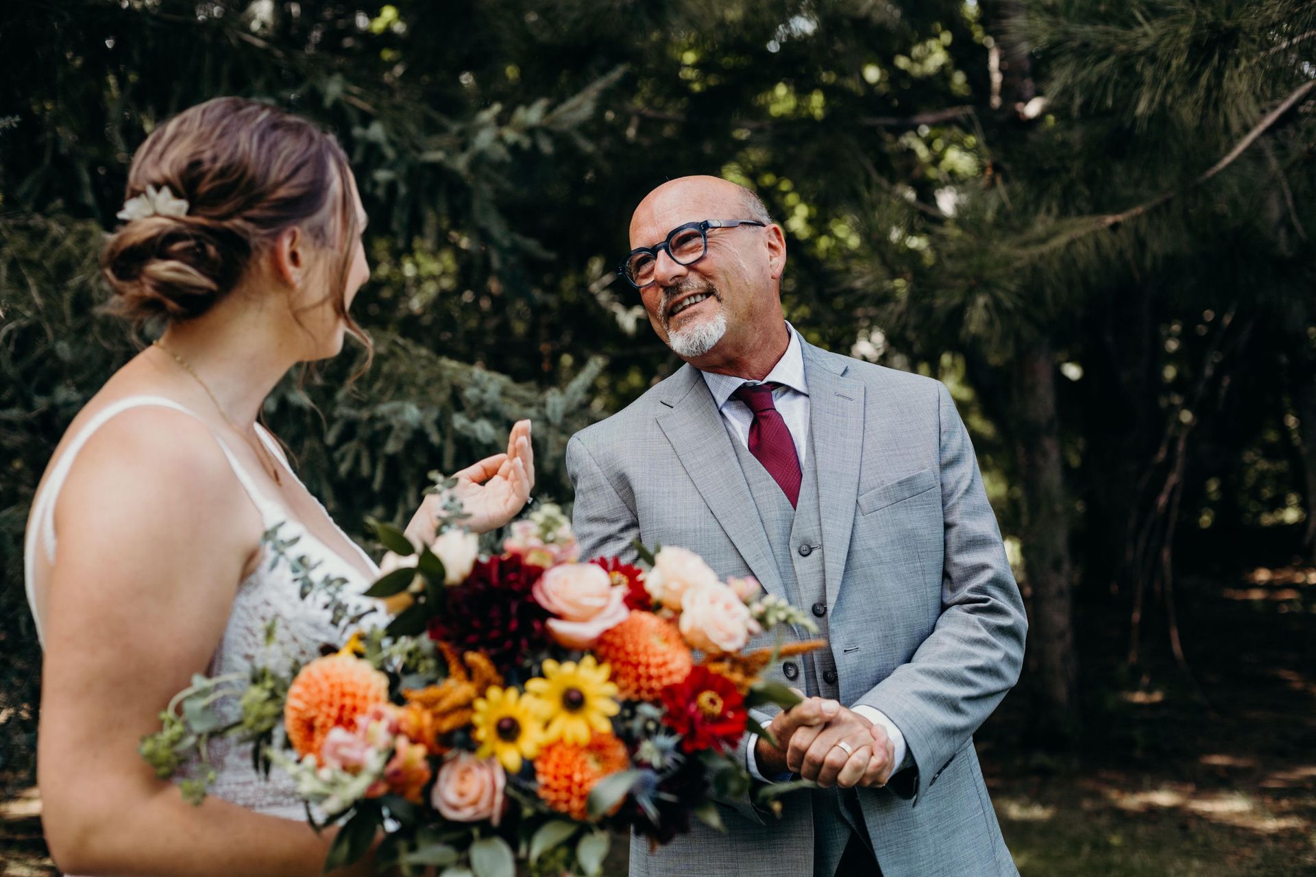 a man in a suit and tie smiles while holding a bouquet of flowers