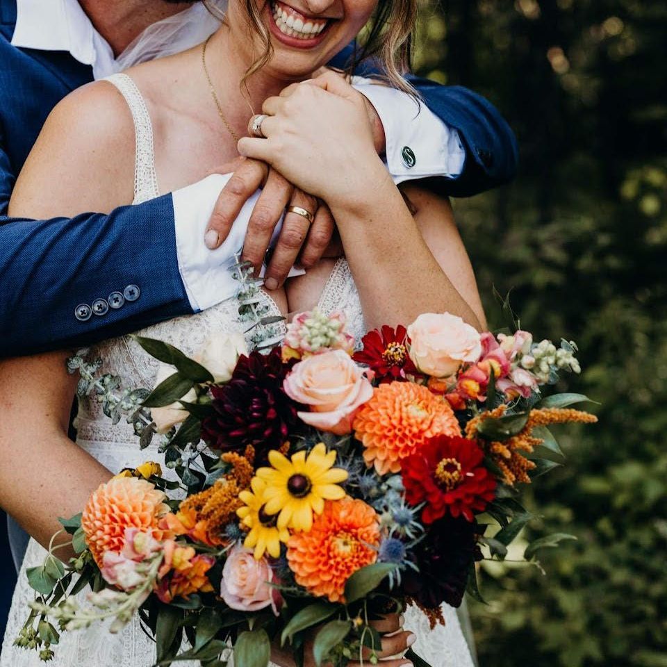 a bride and groom are posing for a picture and the bride is holding a bouquet of flowers