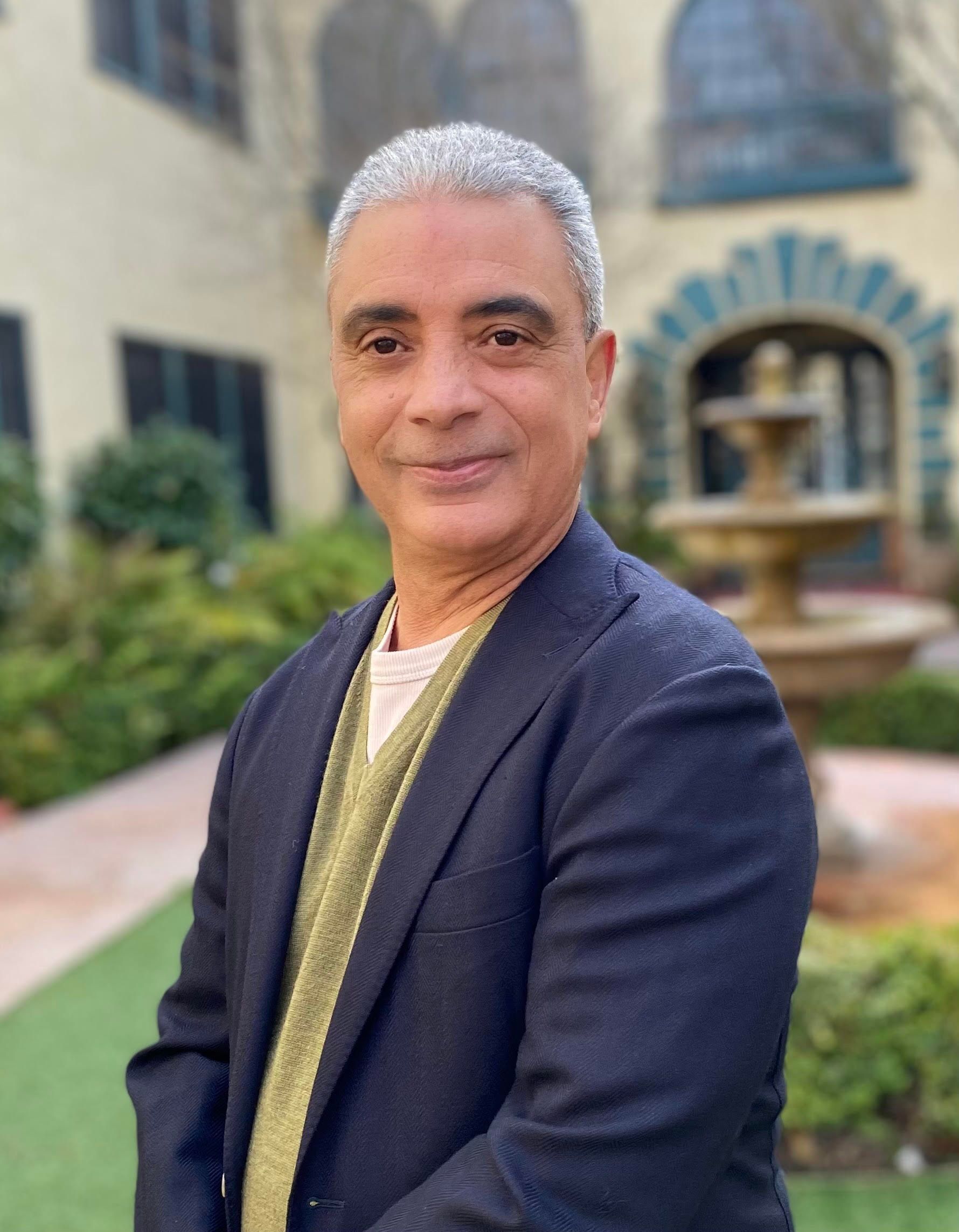 A man in a suit is standing in front of a fountain.