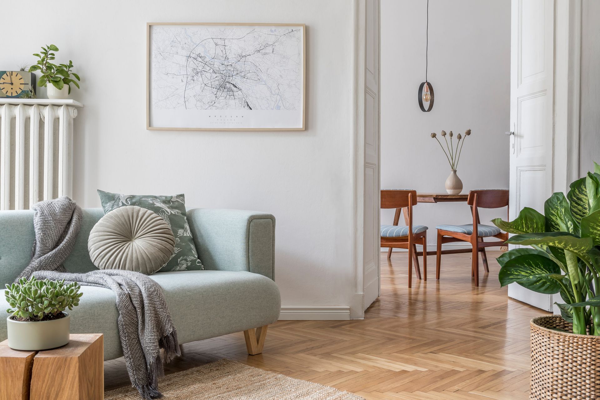 A living room with a couch , table , chairs and plants.