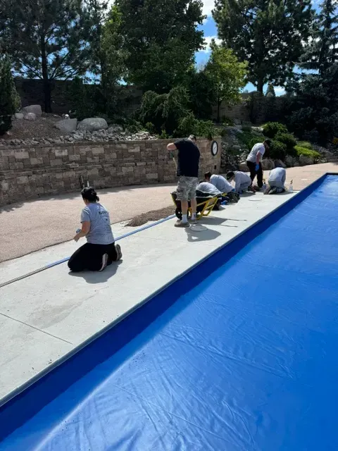 Workers installing surfacing along the pool deck