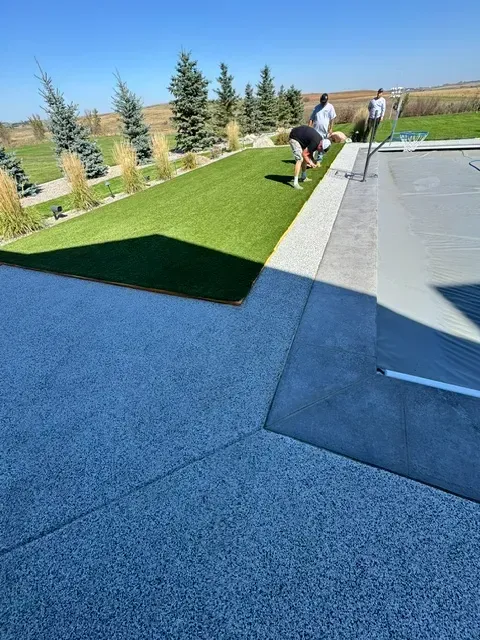 Workers finishing a textured gray pool deck installation