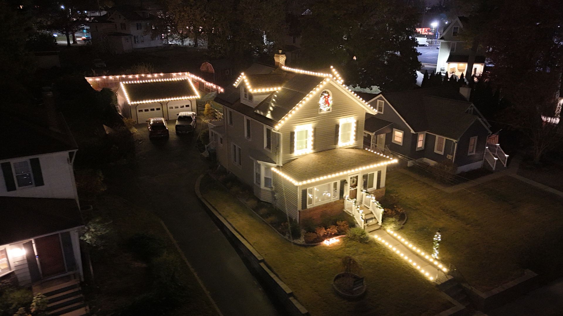 Houses lit with white Christmas lights at night.
