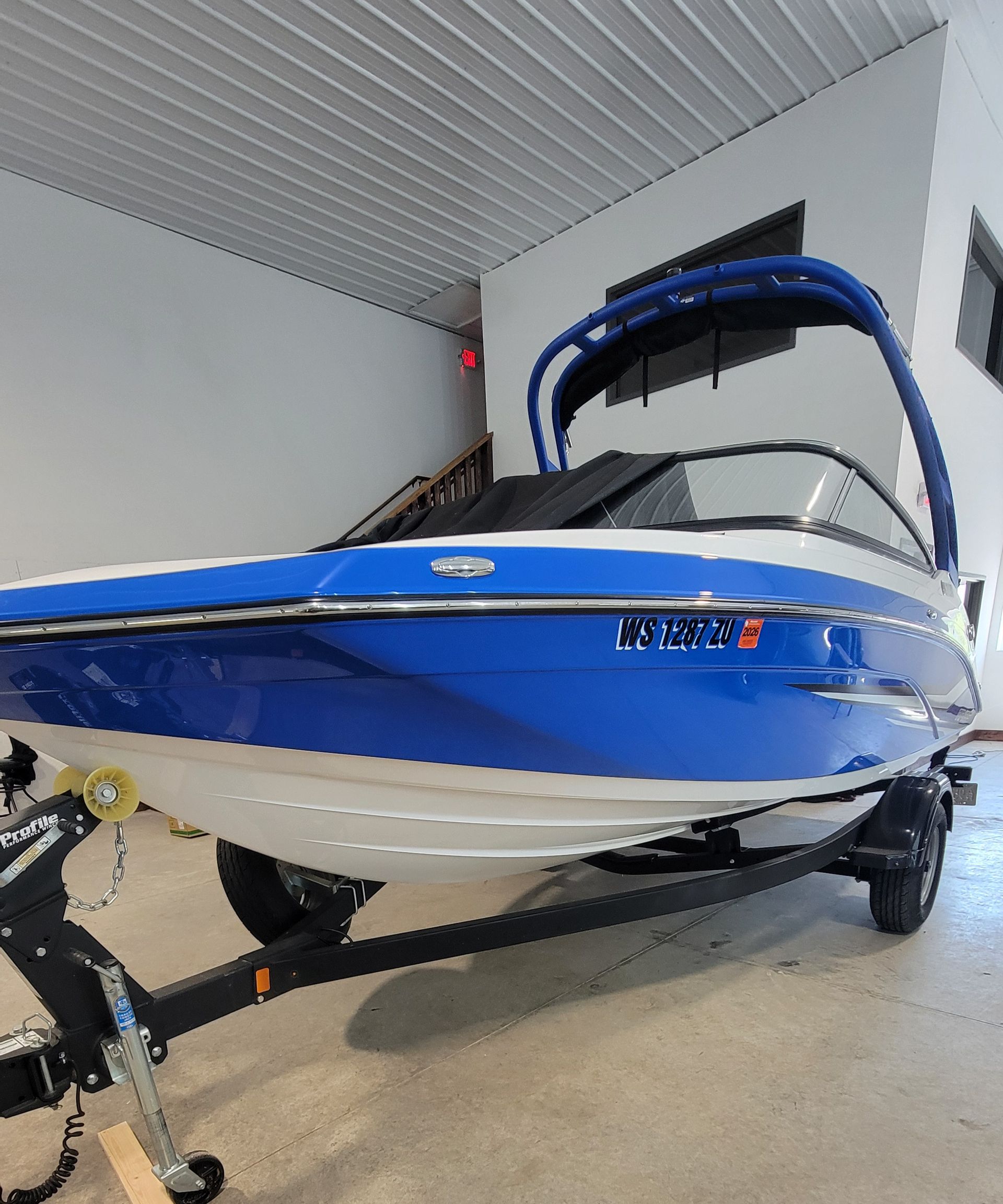 Blue and white speedboat on a trailer inside a covered garage