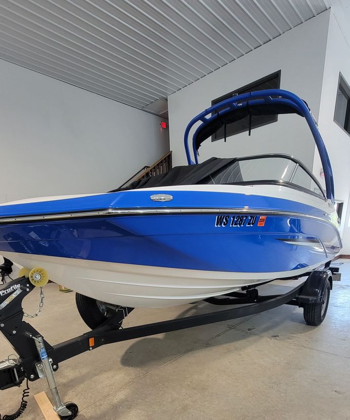 Blue and white speedboat on a trailer inside a covered garage