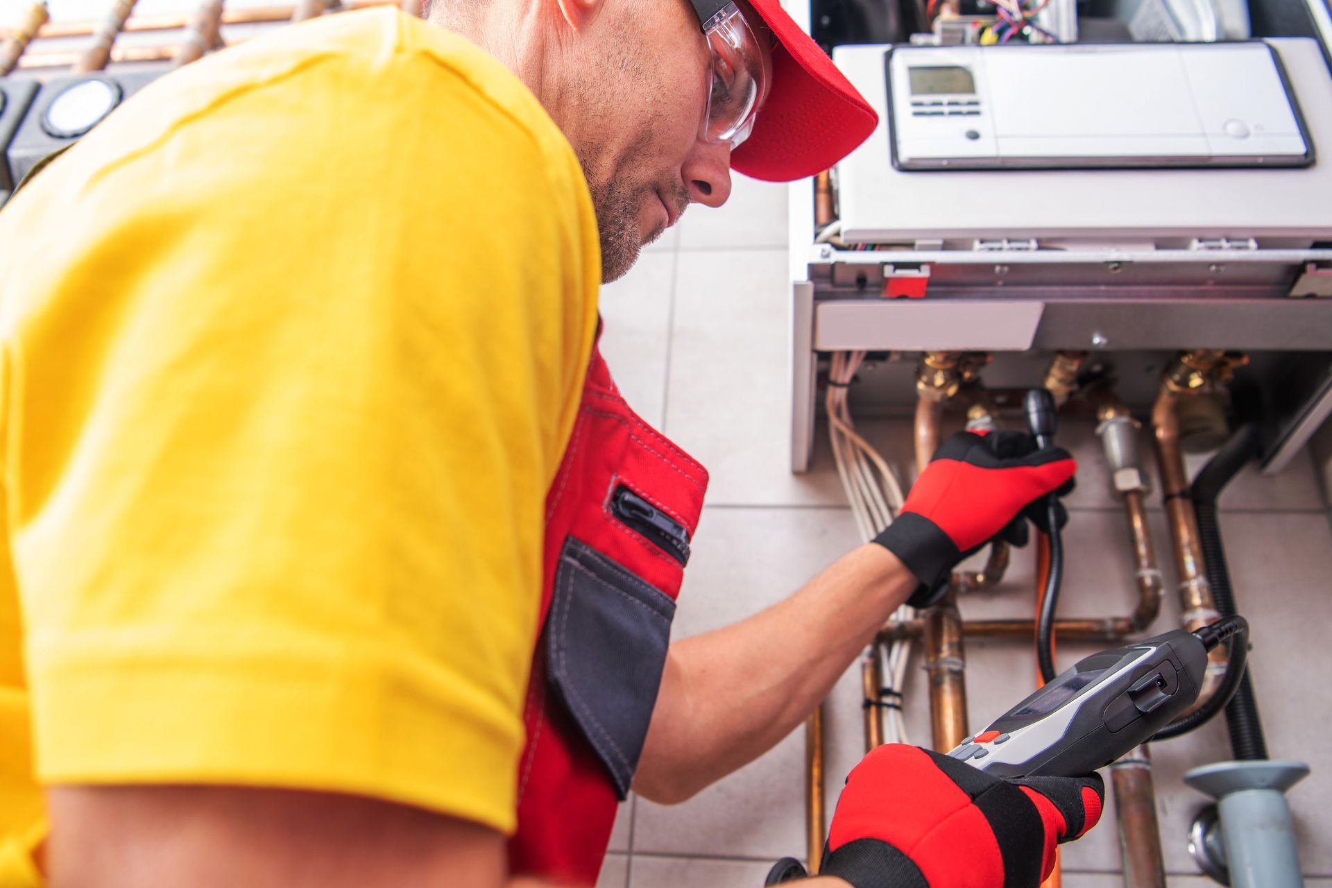 Technician tests and repairs a home water heater using diagnostic tools. Technician tests and repairs a home water heater using diagnostic tools.